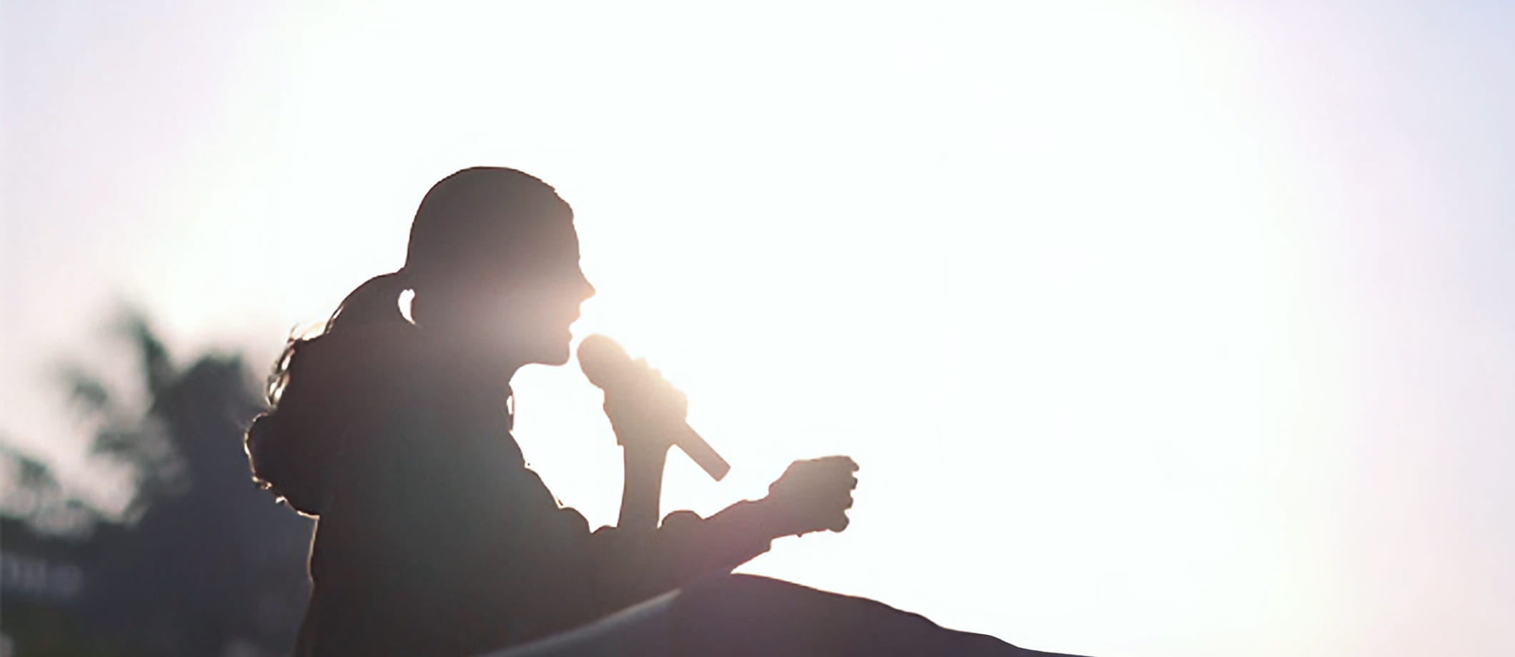 逆光の中でマイクを持ち演説する吉川りな