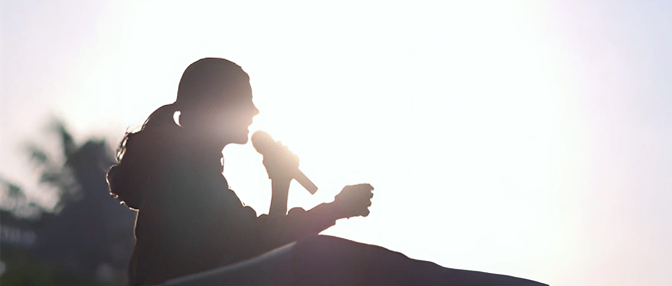 逆光の中でマイクを持って演説する吉川りなのシルエ
                ット